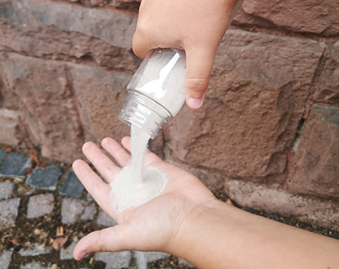 Sand rieselt auf eine Hand.